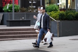 People smoke while they wear protective masks as the coronavirus continues to spread across the United States on March 26, 2020, in New York City.