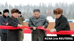 Pemimpin Korea Utara Kim Jong Un didampingi oleh Pak Pong Ju, wakil ketua Komisi Urusan Negara DPRK, memotong pita saat upacara di kotapraja Kabupaten Samjiyon, Korea Utara. (Foto: KCNA via REUTERS)