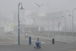 A street performer sits alone at Fisherman's Wharf in San Francisco, March 12, 2020. Sweeping guidelines for Californians to avoid unnecessary gatherings to avoid the spread of the new coronavirus will likely last beyond March, officials say.