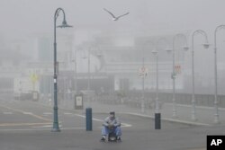 A street performer sits alone at Fisherman's Wharf in San Francisco, March 12, 2020. Gov. Gavin Newsom said sweeping guidance for Californians to avoid unnecessary gatherings to prevent the spread of coronavirus will likely extend beyond March.