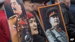 FILE - Communists carry portraits of former Soviet leader Joseph Stalin as they march along Kremlin Towers during a May Day rally in Moscow, May 1, 2015.