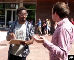 University of Wisconsin freshman Kellen Sharp, left, gets information about registering to vote from NextGen America worker Sean Manning, right, in Madison, Wisconsin, Aug. 30, 2018.