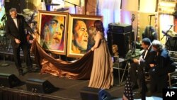 FILE - Muhammad Ali , accompanied by his wife Lonnie Ali, right , receives two portraits of President-elect Barack Obama during an evening on the eve of his inauguration, on Monday, January 19, 2009 in Washington.