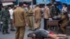 A public order agency officer watches as men do pushups as a punishment for violating the city regulation requiring people to wear face masks in public places to help curb the spread of the coronavirus in Medan, North Sumatra, Indonesia, Sept. 23, 2020.