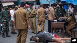 A public order agency officer watches as men do pushups as a punishment for violating the city regulation requiring people to wear face masks in public places to help curb the spread of the coronavirus in Medan, North Sumatra, Indonesia, Sept. 23, 2020.