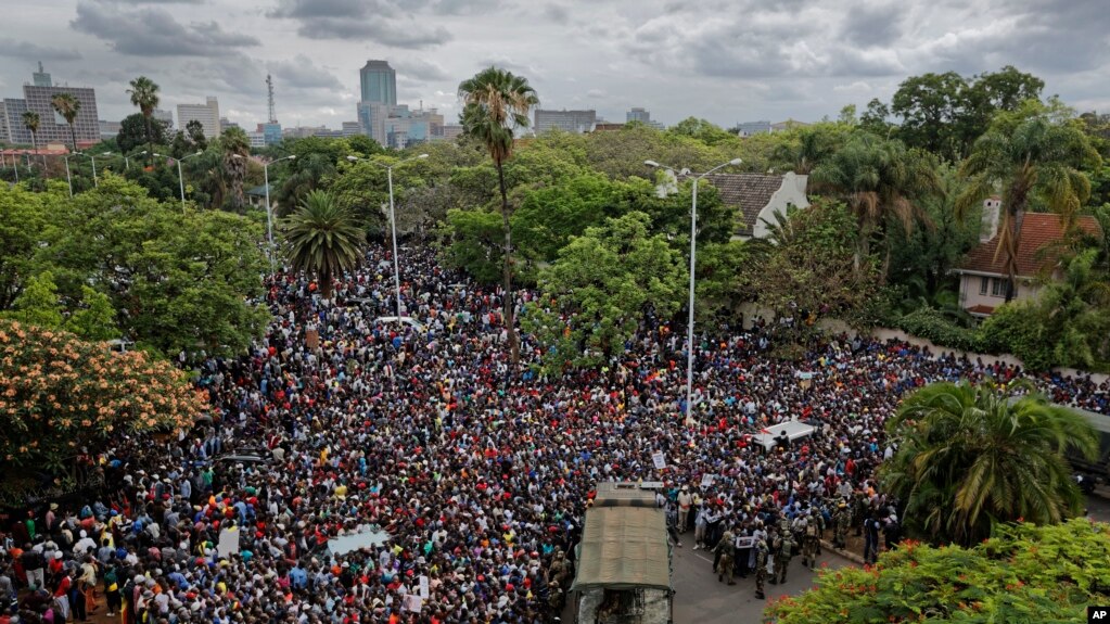 A crowd of thousands of protesters demanding President Robert Mugabe stands down gather behind an army cordon on the road leading to State House in Harare, Zimbabwe Saturday, Nov. 18, 2017.