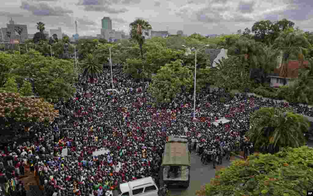 A crowd of thousands of protesters demanding President Robert Mugabe stands down gather behind an army cordon on the road leading to State House in Harare, Zimbabwe Saturday, Nov. 18, 2017.