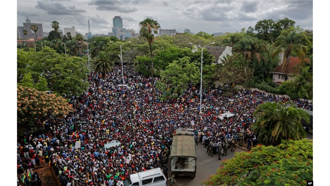 A crowd of thousands of protesters demanding President Robert Mugabe stands down gather behind an army cordon on the road leading to State House in Harare, Zimbabwe Saturday, Nov. 18, 2017.