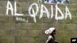 A girl walks past a wall with graffiti about the al-Qaida network in a Muslim area of the northern city of Kano, Nigeria. (File).