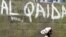 A girl walks past a wall with graffiti about the al-Qaida network in a Muslim area of the northern city of Kano, Nigeria, (File photo).