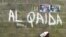 FILE - A girl walks past a wall with graffiti about the al-Qaida network in a Muslim area of the northern city of Kano, Nigeria.