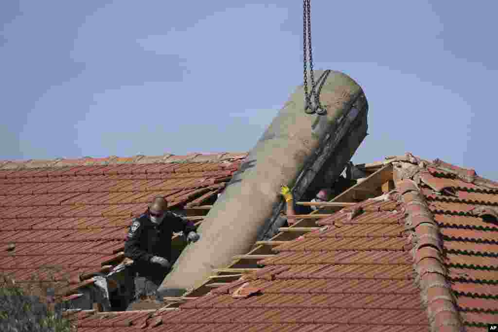 Israeli bomb squad police officers remove part of a missile fired by Yemen&#39;s Houthi rebels after it hit a house in the Israeli village of Mevo Beitar, near Jerusalem.