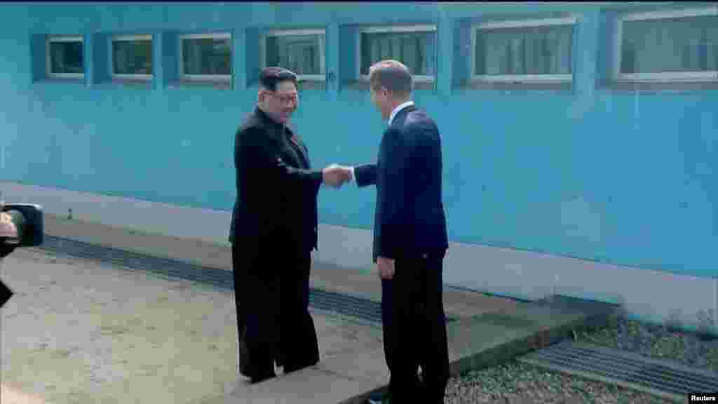 មេដឹកនាំកូរ៉េខាងជើង លោក Kim Jong Un ចាប់រលាក់ដៃជាមួយប្រធានាធិបតីកូរ៉េខាងត្បូងលោកMoon Jae-in នៅឯព្រំដែន គ្រាដែលភាគីទាំងពីរបានទៅដល់ទីកន្លែងសម្រាប់ជំនួបកំពូល នៅភូមិ Panmunjomដែលកិច្ចព្រមព្រៀងបញ្ចប់សង្គ្រាមកូរ៉េជាបណ្តោះអាសន្ន បានធ្វើឡើង។ រូបភាពនេះ ថតចេញពីវីដេអូ នៅកូរ៉េខាងត្បូង នៅថ្ងៃទី ២៧ ខែមេសា ឆ្នាំ២០១៨។