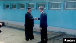 FILE - North Korean leader Kim Jong Un (left) shakes hands with South Korean President Moon Jae-in at the concrete border as both of them arrive for an inter-Korean summit at the truce village of Panmunjom, in this still frame taken from video, South Korea April 27, 2018.
