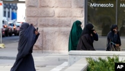 FILE - Female members of Minnesota's Somali community cover their faces as they arrive April 23, 2015, for a detention hearing in federal court in St. Paul in the case of Minnesotans accused of plotting to travel to Syria to join the Islamic State group.