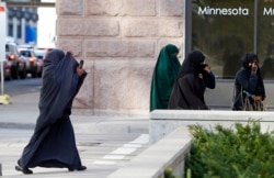 FILE - Female members of Minnesota's Somali community cover their faces as they arrive April 23, 2015, for a hearing in federal court in St. Paul, Minnesota, in the case of several Minnesotans accused of plotting to join jihadists.