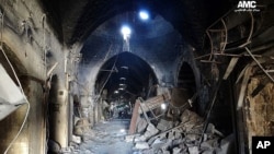 A citizen journalism image provided by Aleppo Media Center AMC which has been authenticated based on contents and AP reporting, shows Syrian rebels standing in the middle of a medieval market in Old Aleppo, which has been destroyed by fighting.