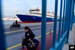 FILE - A passenger walks past a docked ship in the port of Piraeus, near Athens, Greece, Nov. 10, 2021.
