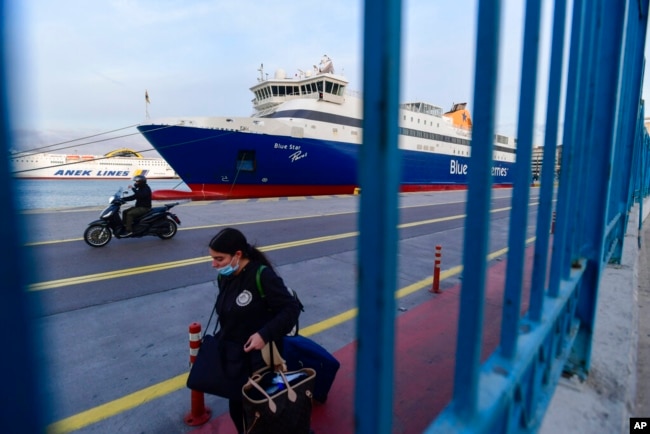 FILE - A passenger walks past a docked ship in the port of Piraeus, near Athens, Greece, Nov. 10, 2021.