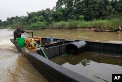 FILE - A suspected oil thief rides a wooden boat full of stolen crude oil on the creeks of Bayelsa, Nigeria, Saturday, May 18, 2013.