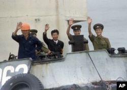 FILE - North Korean port officials wave from their launch as it approaches a South Korean ship near Yanghwa, North Korea, Aug. 19, 1997. Outsiders had been permitted to enter North Korea to attend a groundbreaking for construction of two light water nuclear reactors funded and built by South Korea, the U.S. and Japan. Then and in earlier years, North Korea was expanding economic relations with the West.
