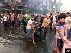 Iraqi firefighters and civilians carry bodies of victims killed in a car bomb at a commercial area in Karrada, Baghdad, July 3, 2016.