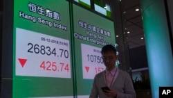 A man walks past an electronic board showing Hong Kong share index outside a local bank in Hong Kong, Wednesday, Dec. 5, 2018. 