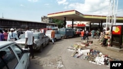 Mituka na bakumbi na yango basali molongo mpo na kozela essence na satation service na Kinshasa, 15 mai 2000.