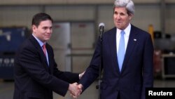 Colombia's Defense Minister Juan Carlos Pinzon (L) shakes hands with U.S. Secretary of State John Kerry during a visit to the anti-narcotics department in Bogota, August 12, 2013. 