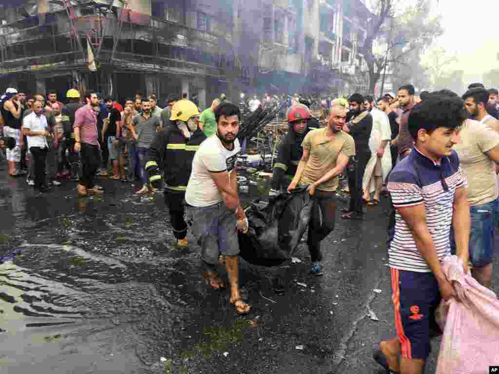 Iraqi firefighters and civilians carry bodies of victims killed in a car bomb at a commercial area in Karrada, Baghdad, July 3, 2016.