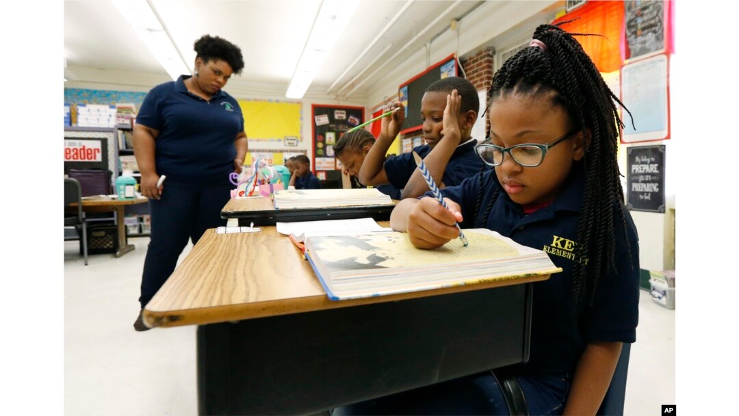 Elize'a Scott, a Key Elementary School third grade student, right, reads under the watchful eyes of teacher Crystal McKinnis, left, Thursday, April 18, 2019, in Jackson, Miss. (AP Photo/Rogelio V. Solis)