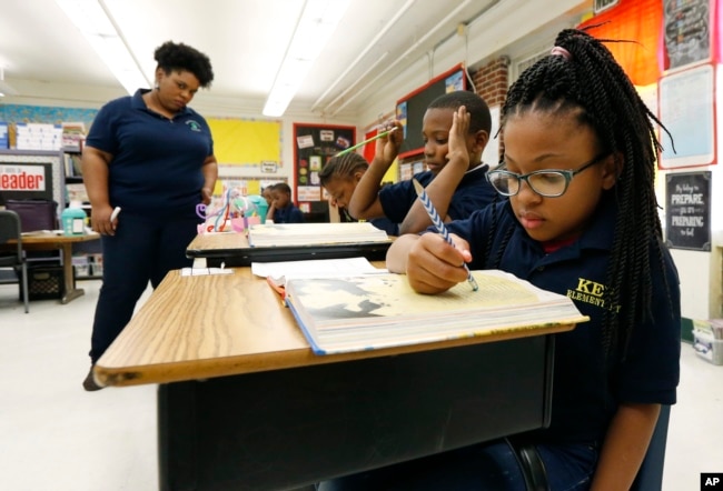 Elize'a Scott, a Key Elementary School third grade student, right, reads under the watchful eyes of teacher Crystal McKinnis, left, Thursday, April 18, 2019, in Jackson, Miss. (AP Photo/Rogelio V. Solis)