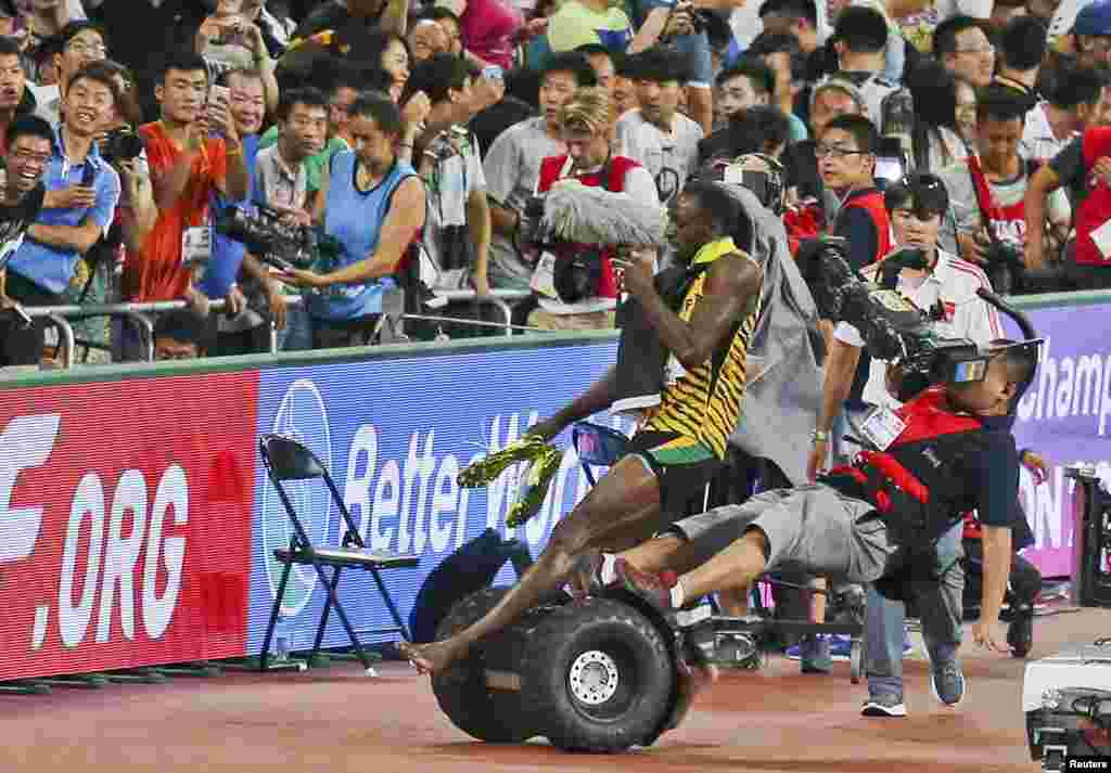 Usain Bolt of Jamaica is hit by a cameraman on a Segway as he celebrates after winning the men&#39;s 200 meters final at the 15th IAAF World Championships at the National Stadium in Beijing, China, Aug. 27, 2015.