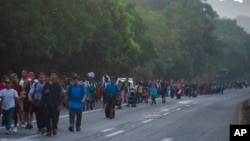 Migrants walk along the highway from Huehuetan to Huixtla in Chiapas state, Mexico, Nov. 19, 2021, on the second day of their journey from Tapachula, toward the northern states of Mexico and the US border. 