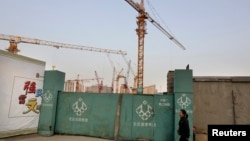 A woman walks along a construction site in Beijing's central business district, Oct. 21, 2014.