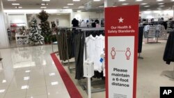 A social-distancing sign reminds shoppers to stay apart as a Christmas trees display stands at the end of walkway in a Macy's department store Thursday, Oct. 1, 2020, in northeast Denver. Retailers such as Macy's are already putting out holiday items for 