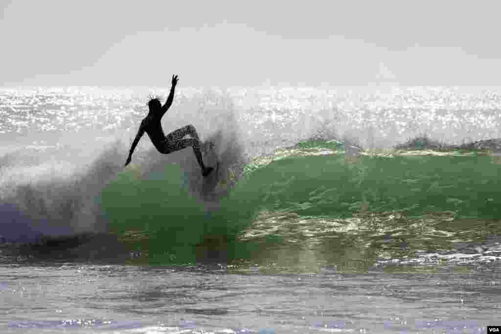 Pape Diouf, a Senegalese surfboard shaper, surfs in waters off Dakar, Senegal. (Annika Hammerschlag/VOA)