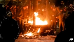 Protesters warm up next to a burning kiosk after minor clashes erupted during a protest in Bucharest, Romania, Feb. 2, 2017.