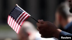 Un candidato a la ciudadanía estadounidense sostiene una bandera durante una ceremonia de naturalización en el Servicio de Ciudadanía e Inmigración, en la Plaza Rockefeller de Nueva York, el 17 de septiembre de 2019. 