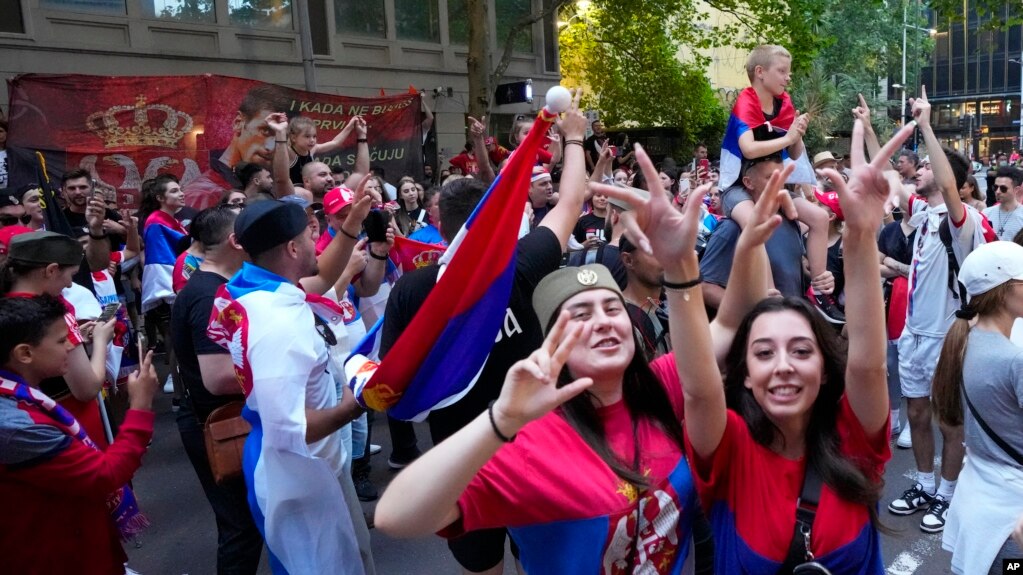 Fans dance and sing outside an immigration detention hotel where Serbian Novak Djokovic is confined in Melbourne, Australia, Monday, Jan. 10, 2022. (AP Photo/Mark Baker)