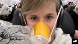 This image provided by Kelly Bartlett shows Bartlett wearing an oxygen mask on an Alaska Airlines Boeing 737 Max 9, Flight 1282, which was forced to return to Portland International Airport after the jetliner blew out a portion of its fuselage on Jan. 5, 2024.