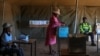 A voter casts her ballot as an electoral official and a Botswana Police officer look on at the Gaborone Block 8 polling station in Gaborone on October 30, 2024, during Botswana's general election.