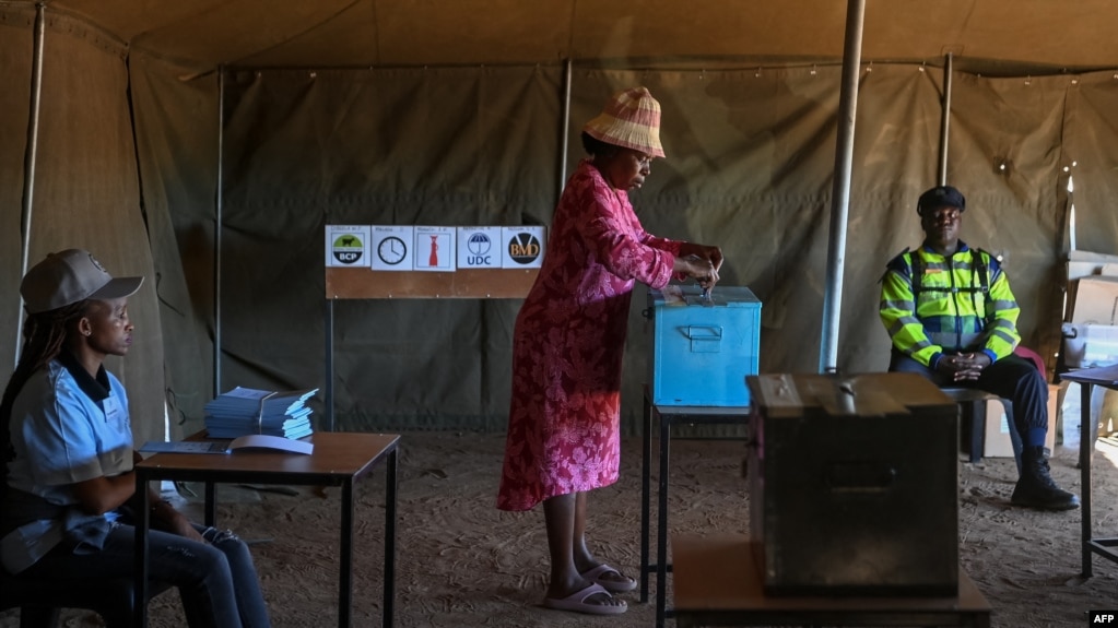 A voter casts her ballot as an electoral official and a Botswana Police officer look on at the Gaborone Block 8 polling station in Gaborone on October 30, 2024, during Botswana's general election.