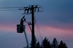 FILE - In this Nov. 26, 2018, file photo, a Pacific Gas & Electric lineman works to repair a power line in fire-ravaged Paradise, Calif.
