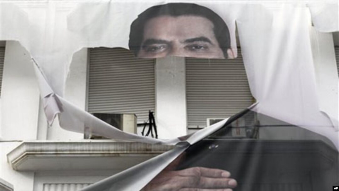 A torn banner of former Tunisian President Zine El Abidine Ben Ali is seen in the center of Tunis, 16 Jan 2011