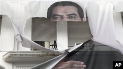 A torn banner of former Tunisian President Zine El Abidine Ben Ali is seen in the center of Tunis, 16 Jan 2011