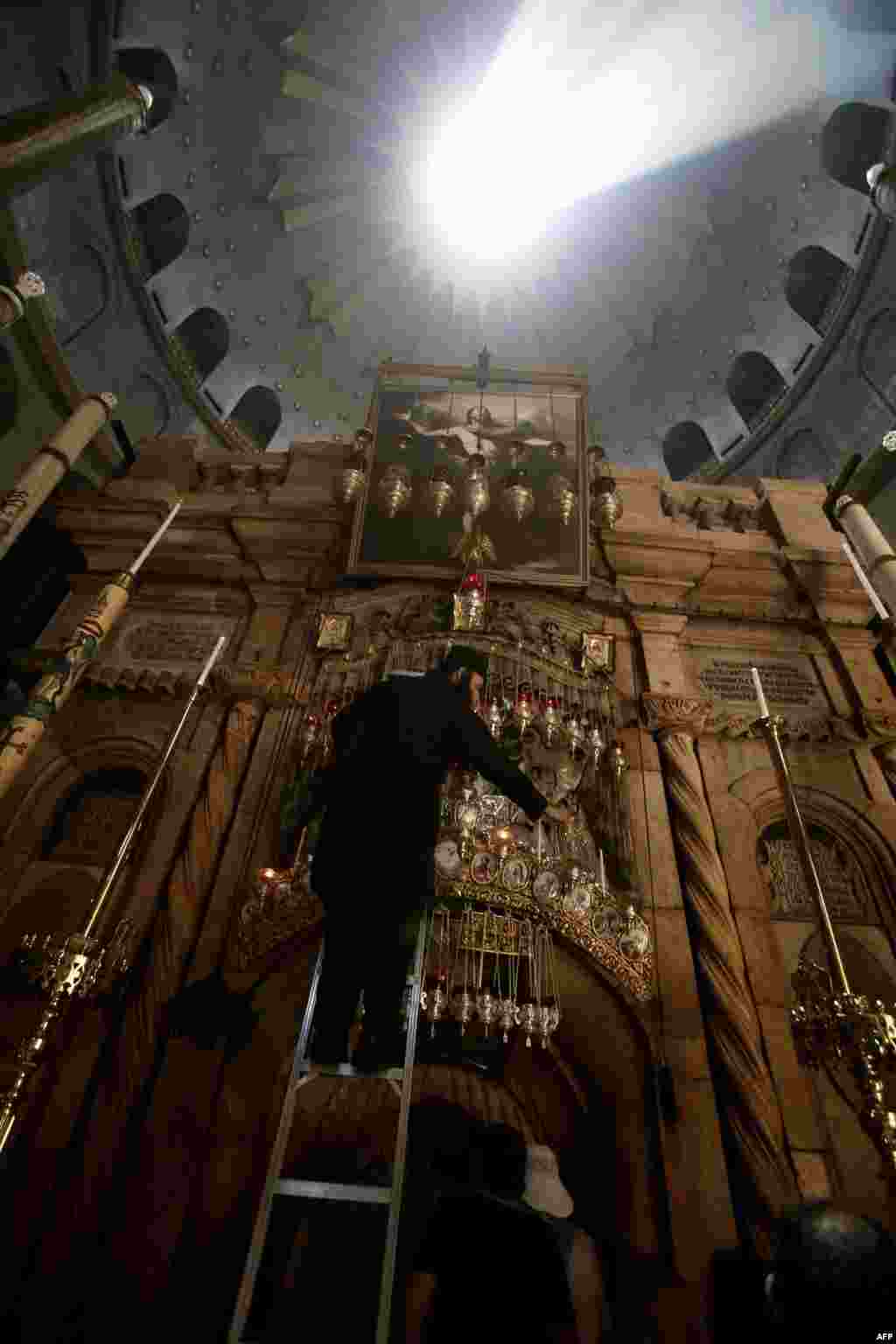 Một tu sĩ Chính thống giáo Hy Lạp rót dầu vào đèn tại mộ của Chúa Giêsu ở nhà thờ Mộ Thánh trong Cổ thành của Jerusalem, hai ngày trước chuyến viếng thăm của Đức Giáo hoàng Phanxicô đến Đất Thánh. 