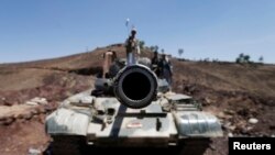 A frontal view of a tank barrel is seen as Shi'ite Houthi rebels stand on its turret, after they took over the compound of the army's First Armored Division in Sana'a, Yemen, Sept. 22, 2014. 