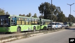 Buses carrying gunmen leave the Waer neighborhood, in the central city of Homs, Syria, as part of a local deal with government forces that allows them safe passage to areas in the country's north, Dec. 9, 2015.