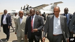 A delegation from South Sudan, headed by Pagan Amum, center, walks with Sudan's Idris Mohamed Abdul-Gadir, right, after their arrival in Khartoum, Sudan, (March 22, 2012 file photo) 